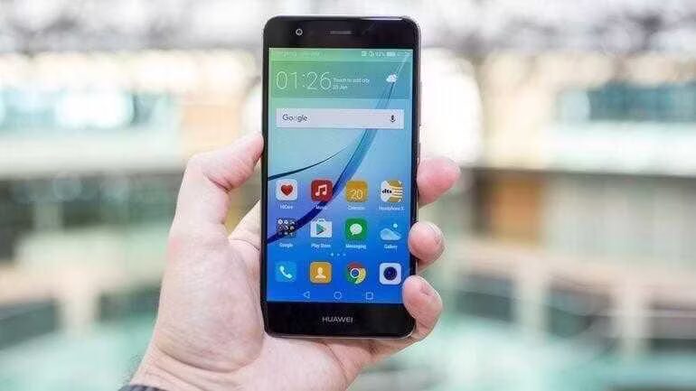 Рука держит Huawei Nova на фоне стеклянной конструкции
