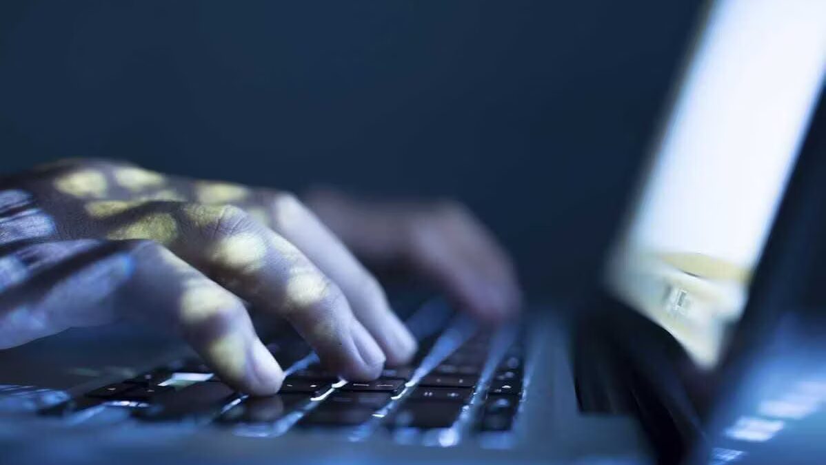 Рука пользователя на клавиатуре ноутбука при работе в темной среде