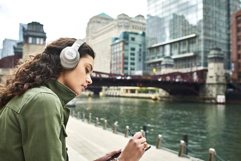Девушка с наушниками JBL возле городской реки
