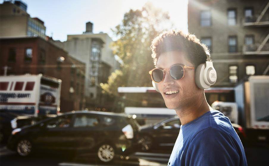 Мужчина в затемненных очках и наушниках JBL на улице