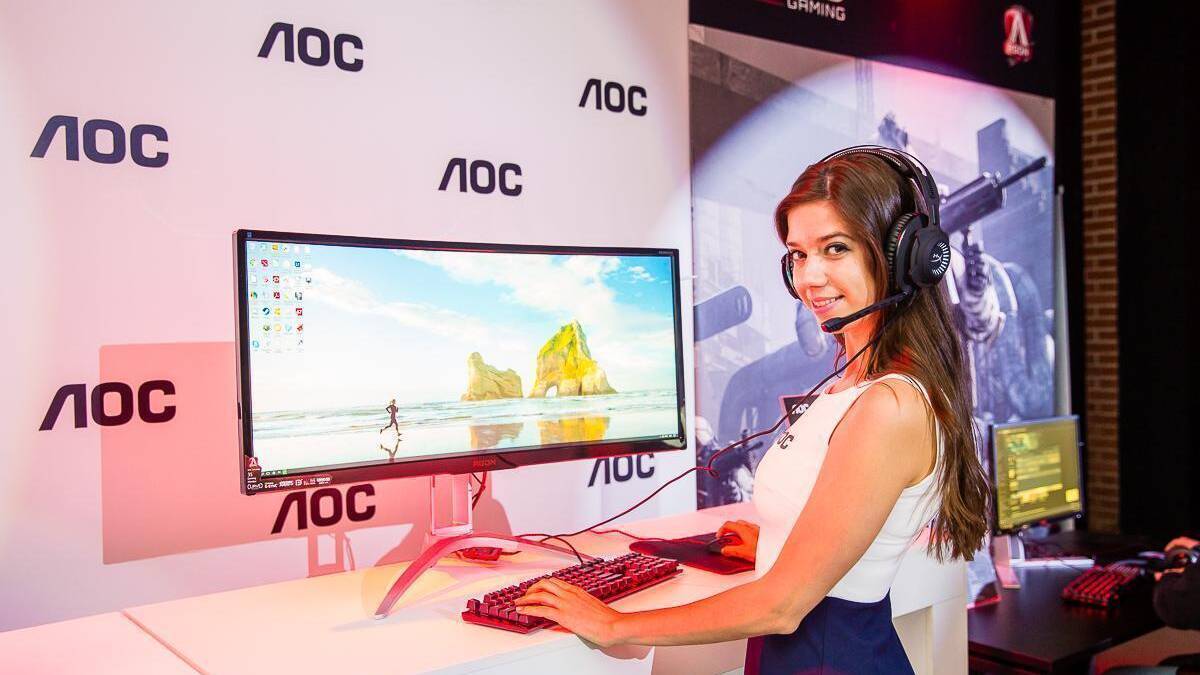 женщина на выставке с монитором AOC и гарнитурой