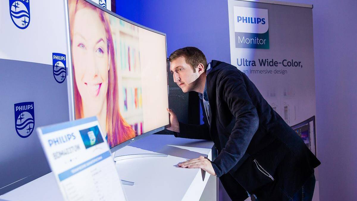 Philips рассказал про тренды в производстве мониторов 7 Мужчина рассматривает ультраширокий монитор Philips в выставочном зале