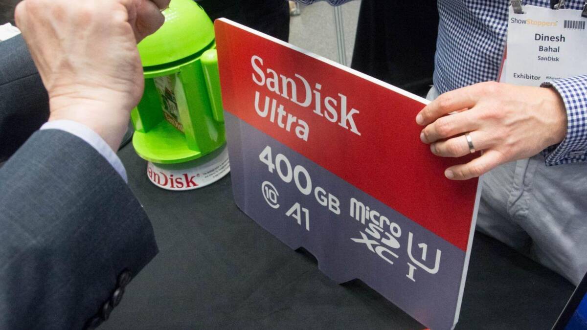 Человек показывает рекламный стенд Sandisk Ultra с памятью 400 ГБ на выставке