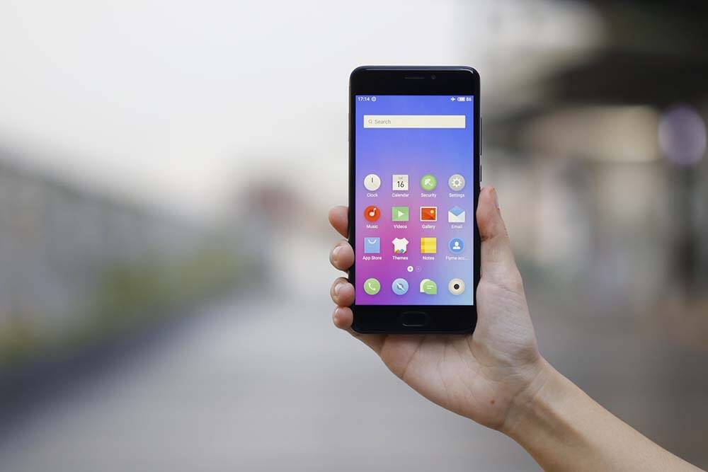 Рука держит смартфон ZTE с отображением приложений на экране