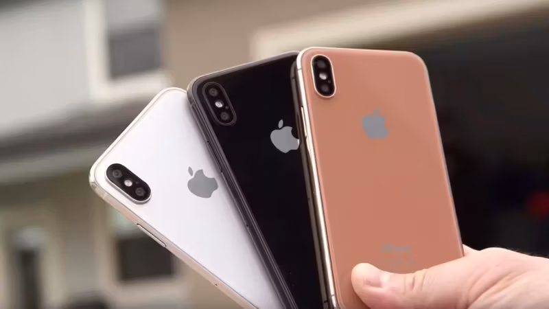Три iPhone 8 разных цветов в руке крупным планом