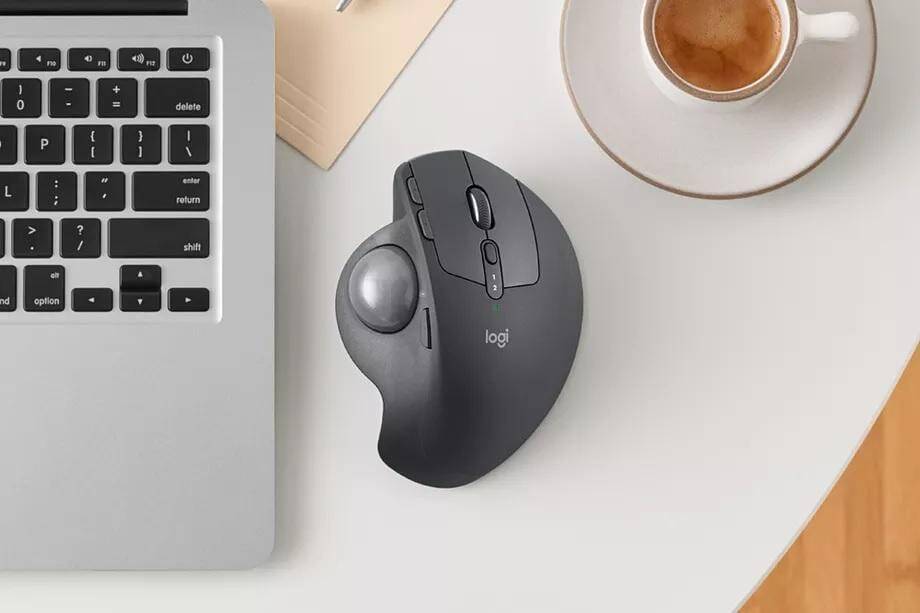 Компьютерная мышь Logitech рядом с ноутбуком и чашкой кофе