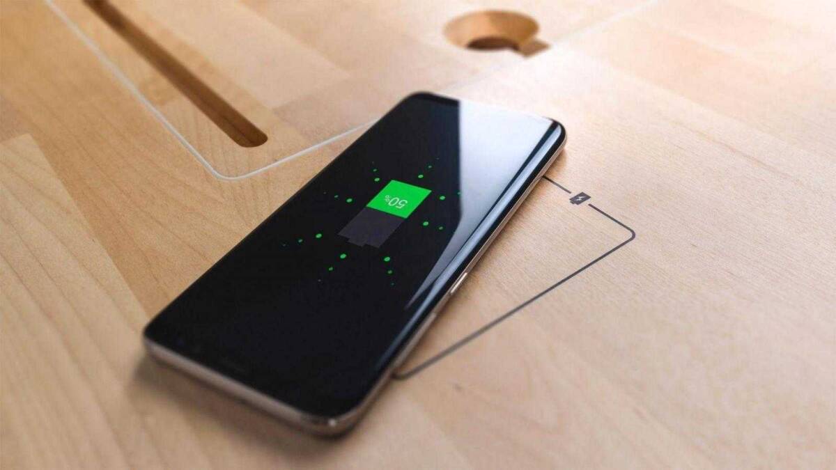 Смартфон с беспроводной зарядкой на деревянном столе