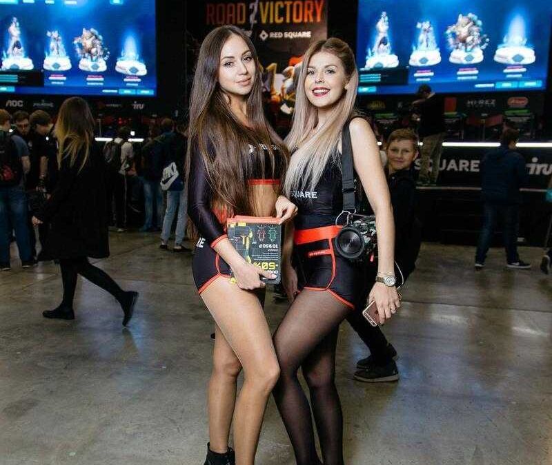 Две девушки на выставке в черных костюмах с графикой iPhone