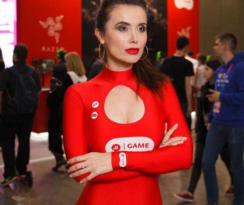 Женщина в красном костюме на выставке с логотипом iGAME