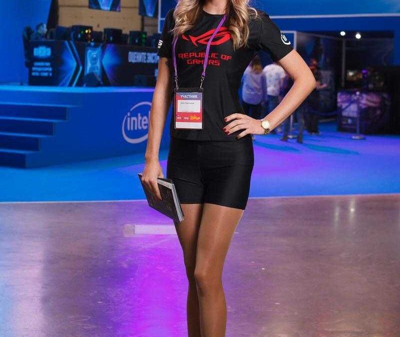 Женщина в черной футболке и мини-юбке на выставке с логотипом Asus ROG