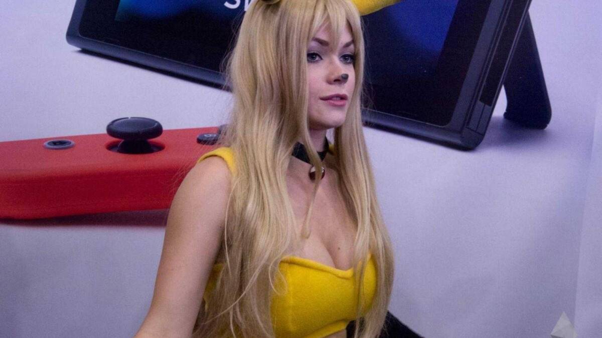18+ Самые красивые девушки ИгроМир 2017 и Comic Con 99 Девушка с длинными светлыми волосами в костюме Пикачу на фоне телевизора и игровой консоли