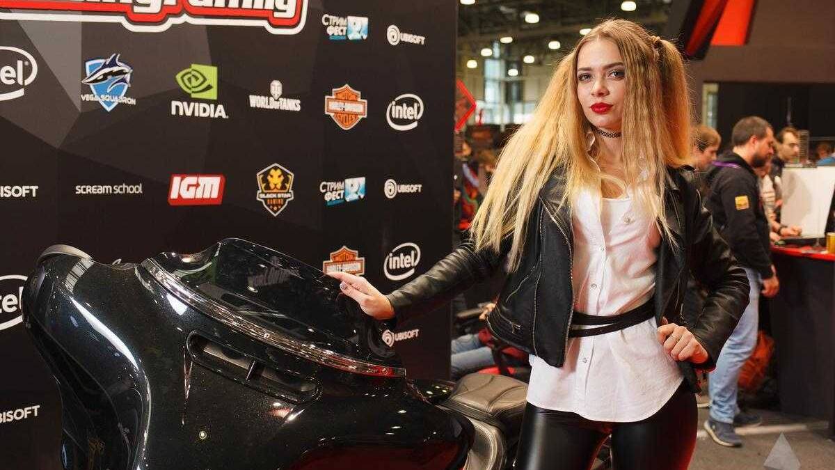 18+ Самые красивые девушки ИгроМир 2017 и Comic Con 59 Девушка в кожаной куртке и черных кожаных брюках рядом с мотоциклом на выставке