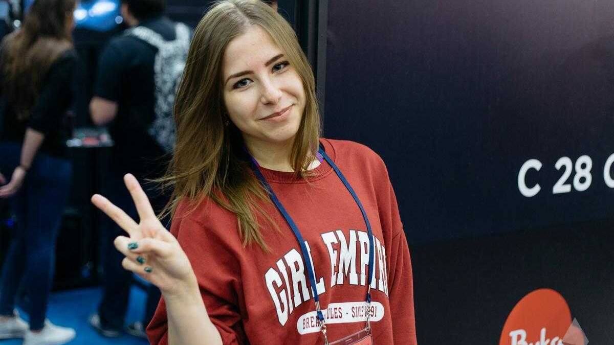 18+ Самые красивые девушки ИгроМир 2017 и Comic Con 92 Женщина в красной толстовке с надписью Girl Empire показывает peace жест и улыбается