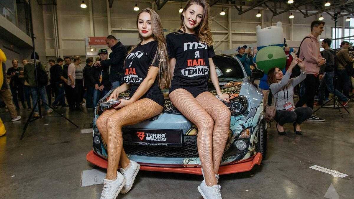 18+ Самые красивые девушки ИгроМир 2017 и Comic Con 91 Две девушки в черных футболках и белых кроссовках сидят на автомобиле на выставке
