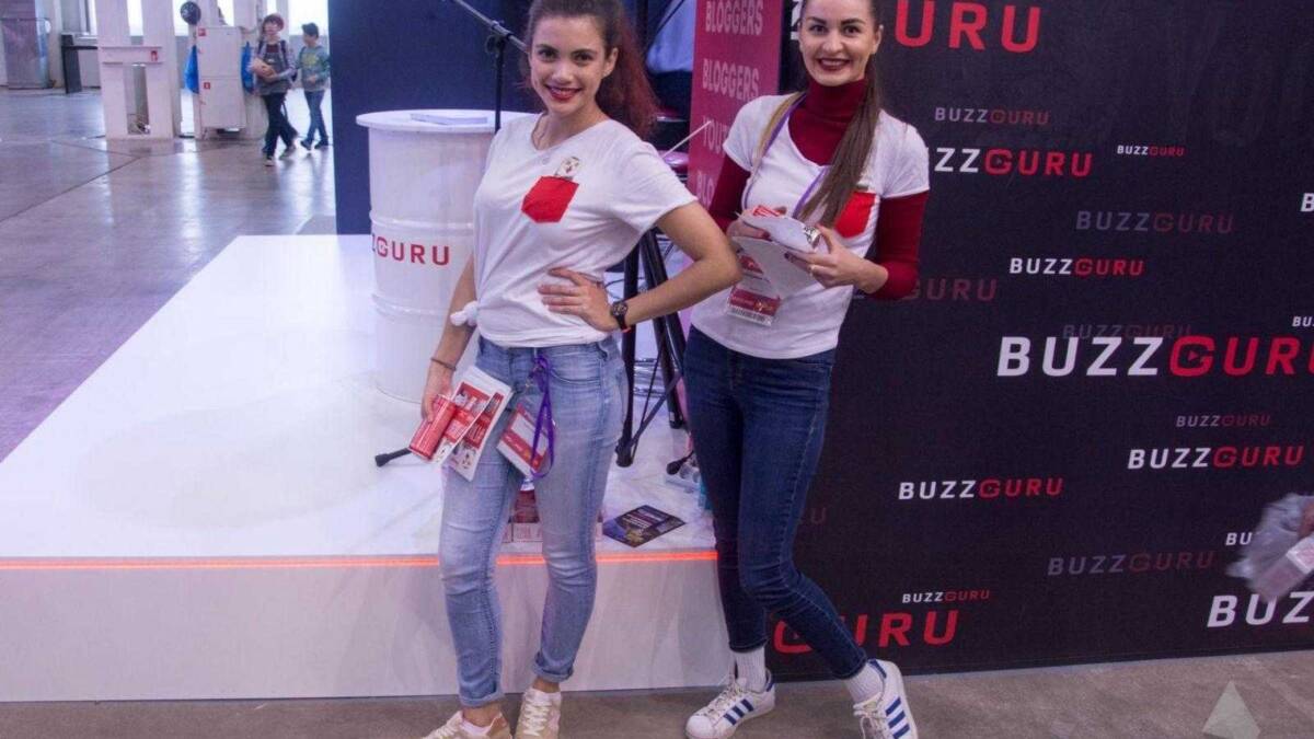 18+ Самые красивые девушки ИгроМир 2017 и Comic Con 104 Две женщины стоят на выставочной стенде с логотипом BuzzGuru