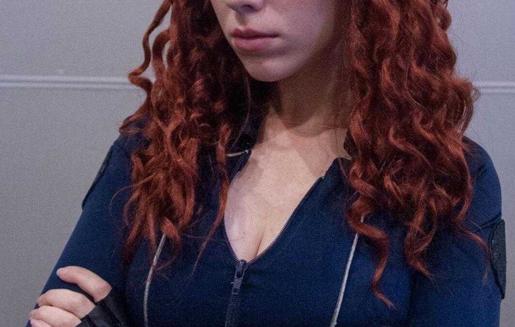 Косплей персонажа с рыжими кудрявыми волосами и синим костюмом