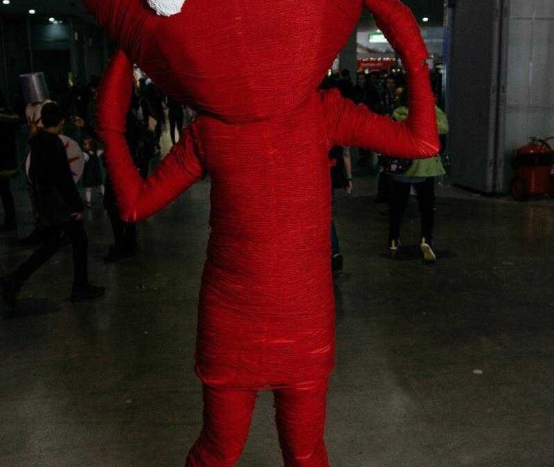 Костюм косплея в виде крупной красной звезды с белыми глазами на голове человека в толпе