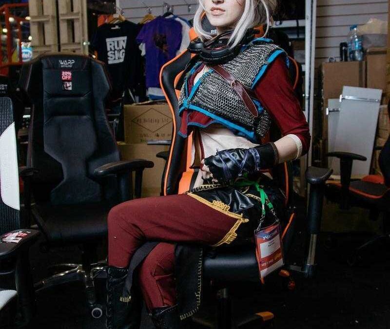 Косплей в стиле видеоигр на ИгроМир 2017 женщина с серо-белыми волосами в костюме с наушниками и кожаными перчатками