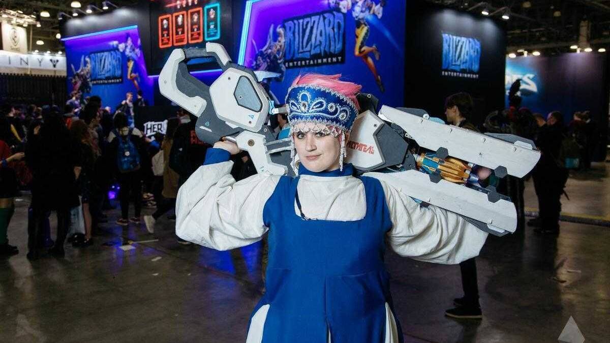 Косплей персонажа из Overwatch с большим оружием сзади