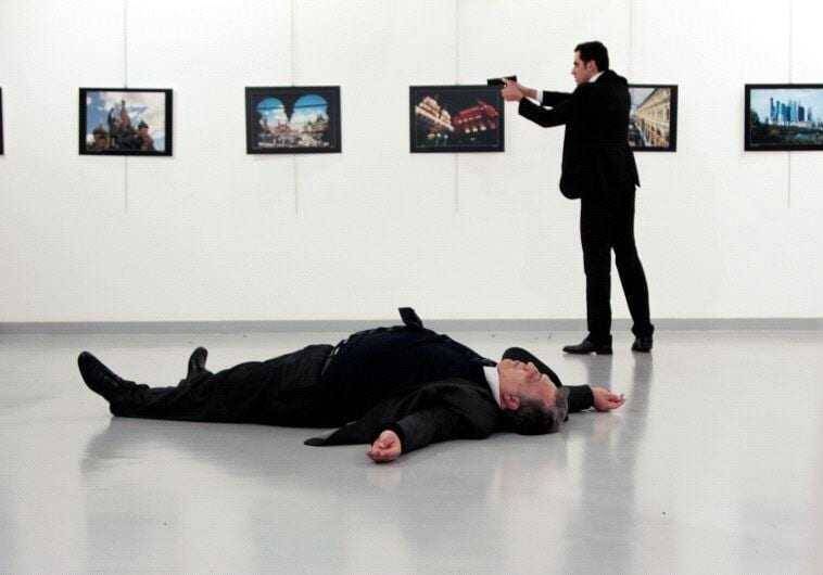 Человек в костюме лежит на полу у выставки фотографий в музее