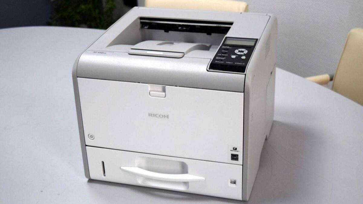 Обзор принтера Ricoh SP 450DN. Быстрая печать для офиса 15 Принтер Ricoh SP 450DN на белом столе вид сбоку