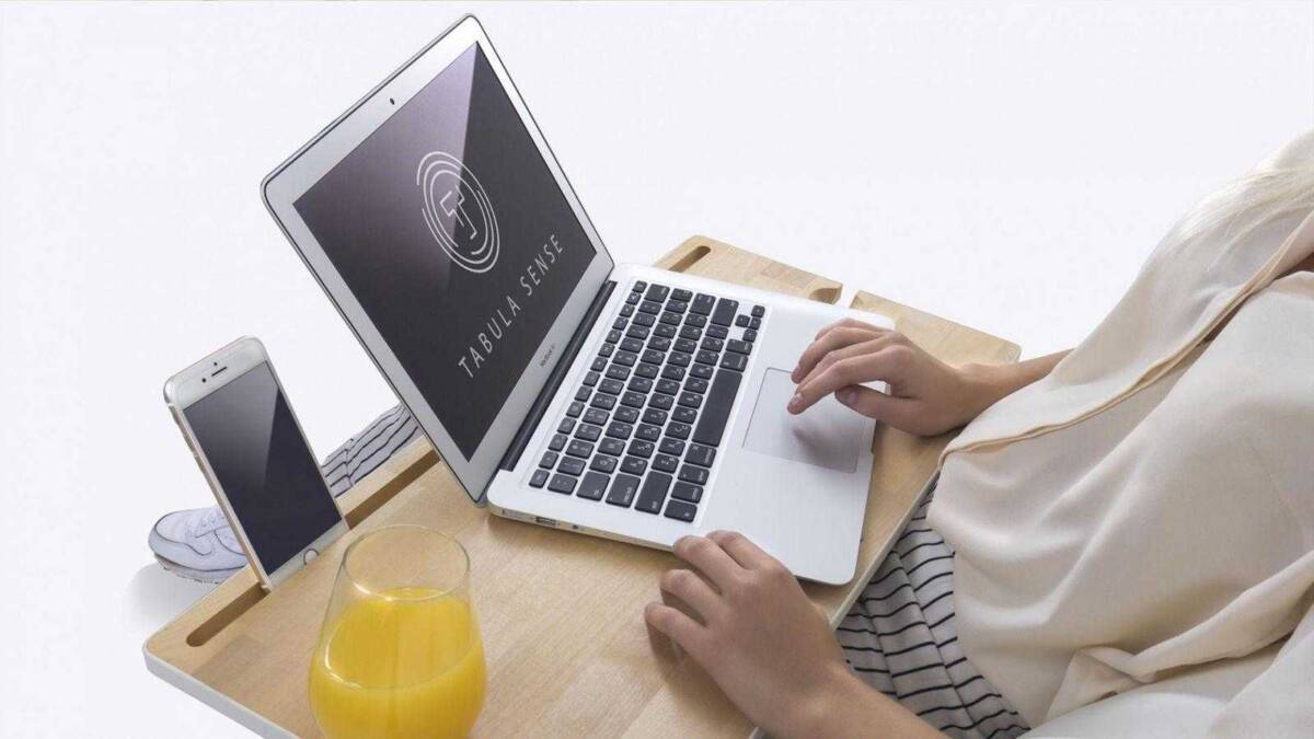 Ноутбук и смартфон на деревянной подставке с планшетом и стаканом сока рядом