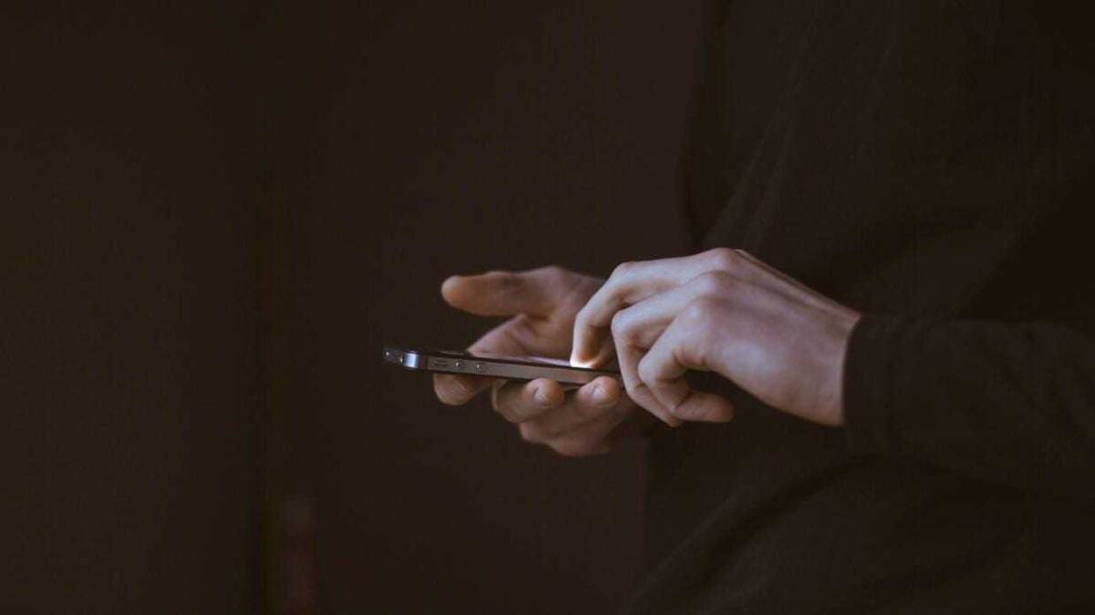 Человек использует смартфон на темном фоне