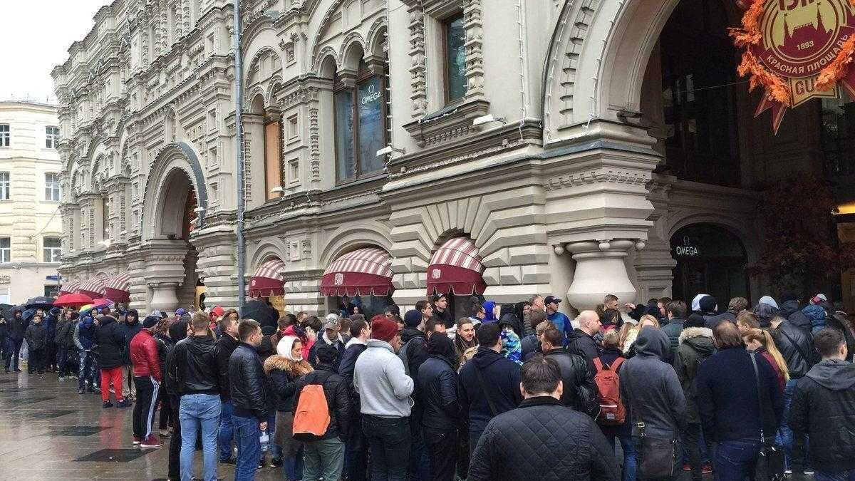 Очередь людей на улице перед магазином с красными зонтами для покупки iPhone X в России