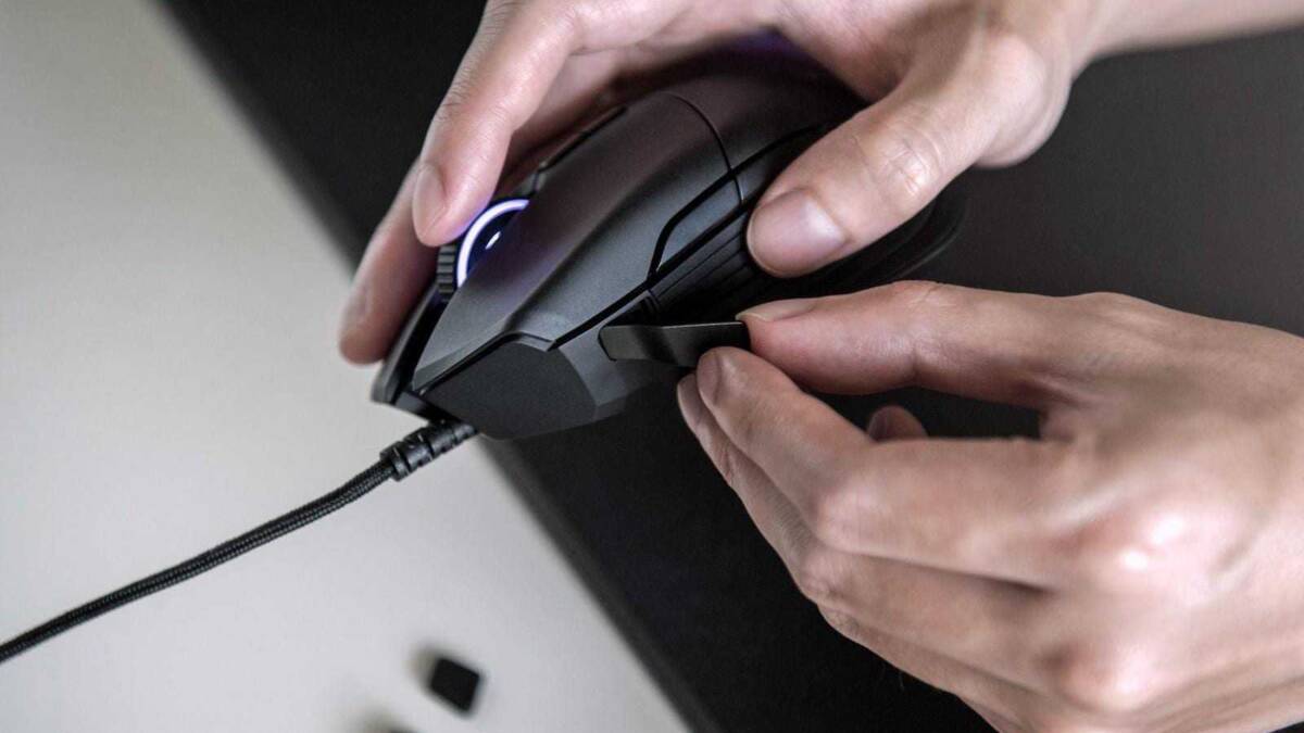 Рука держит игровую мышь Razer Basilisk с подсветкой и кабелем