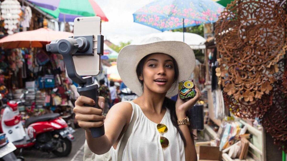 Девушка с шляпой держит стабилизатор DJI Osmo Mobile 2