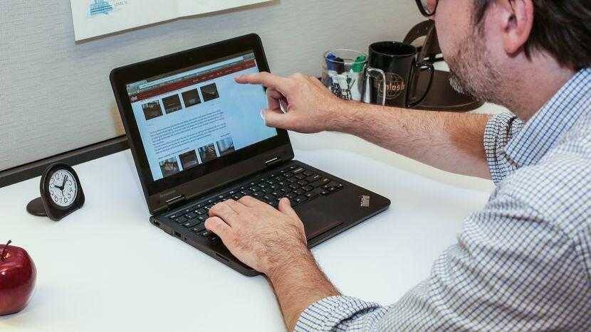 Человек использует ноутбук Lenovo для учебы на рабочем столе