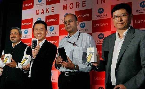 Lenovo закрыла мобильное подразделение в Европе 3 Четыре человека держат смартфоны Lenovo Moto в руке на фоне логотипов Lenovo и Motorola