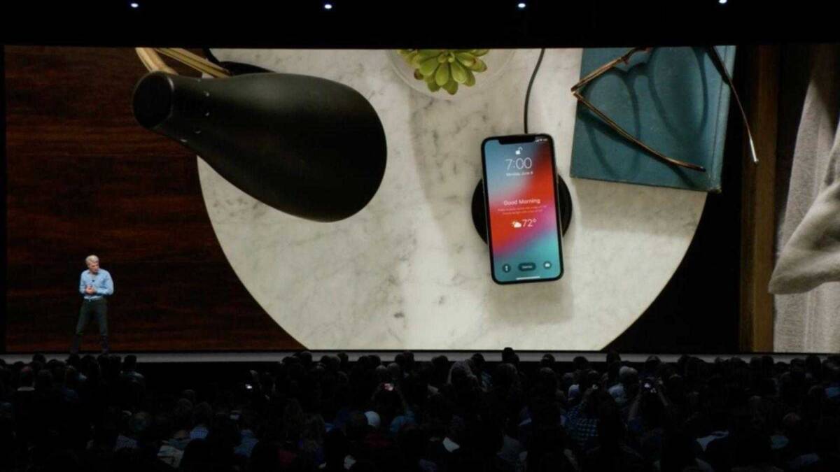 Смартфон iPhone на зарядной подставке и предметы на столе