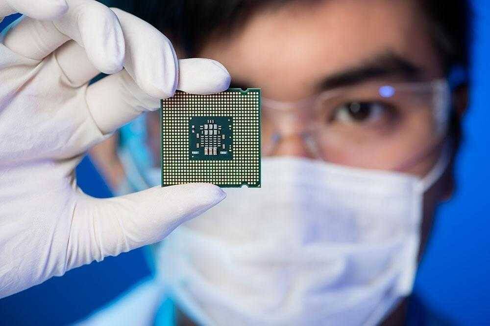 Человек в защитных очках и маске держит процессор Intel нового поколения крупный план