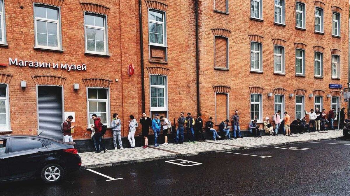 Очередь из людей возле магазина и музея на улице