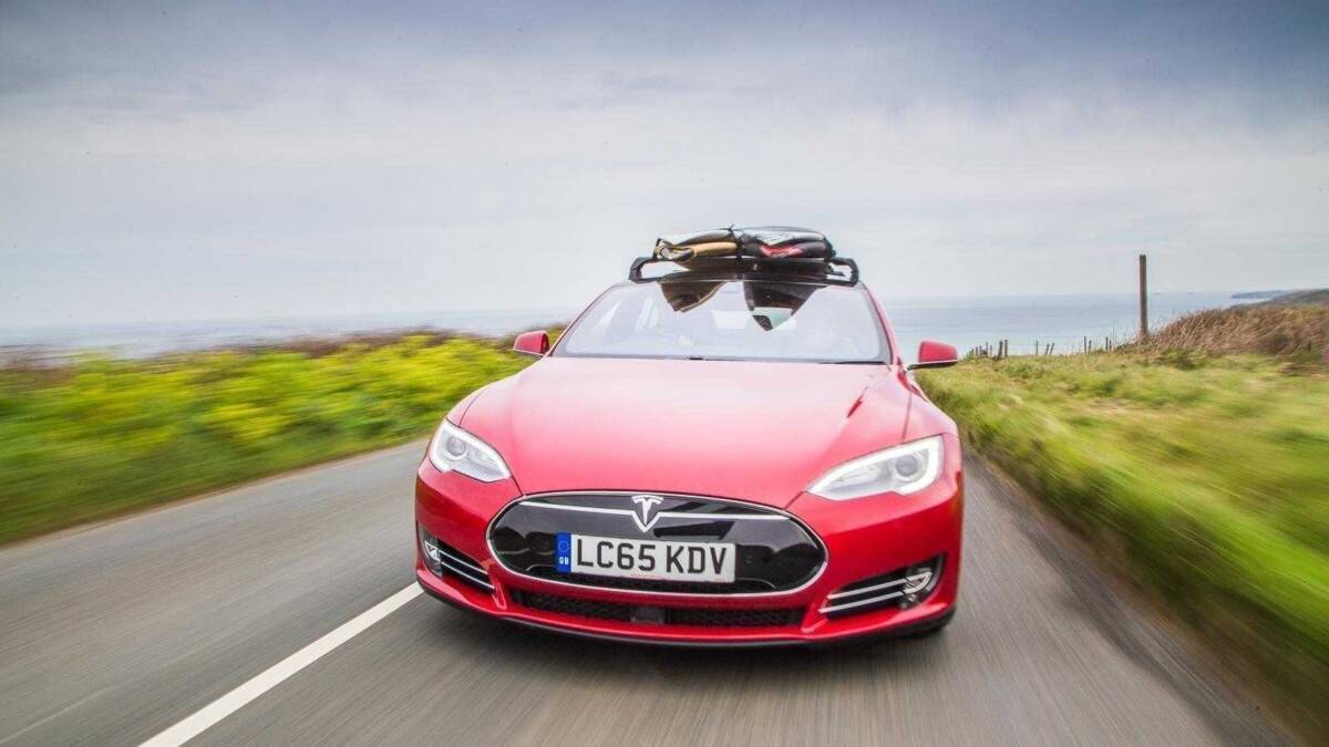 Красный электромобиль Tesla с крышкой для сёрфинга на крыше