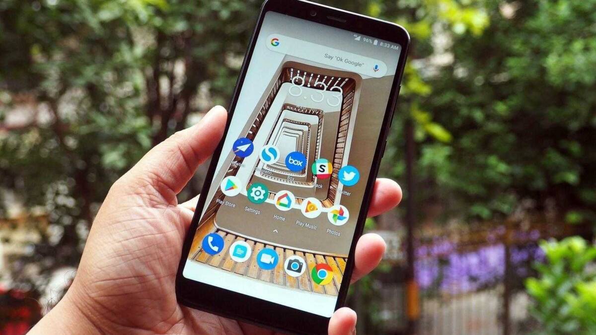 Рука держит смартфон Xiaomi Mi A2 на улице с приложениями на экране