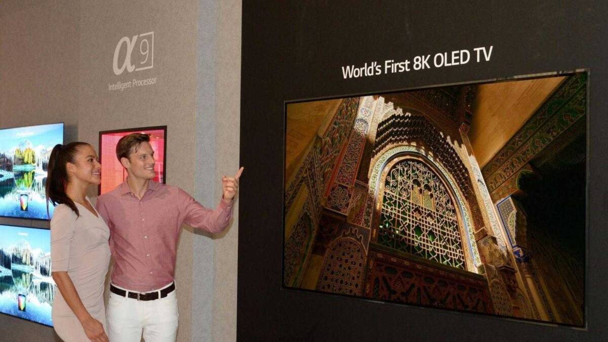 Два человека смотрят на 8K OLED телевизор LG