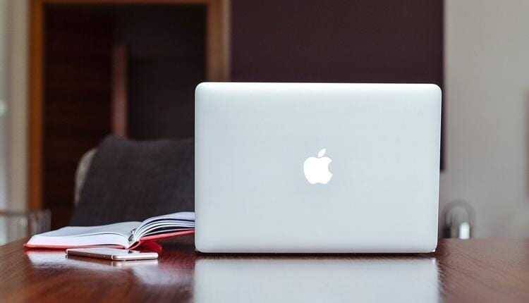 Ноутбук MacBook на деревянном столе с книжками