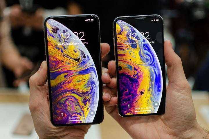 Российские цены на новые Apple iPhone XS, XS Max и XR 3 Два смартфона Apple iPhone XS Max в руках крупным планом на фоне людей