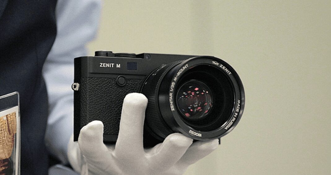 Чёрный фотоаппарат Zenit M в руке человека в белых перчатках