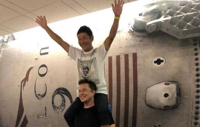 Два человека на фоне стены с логотипом SpaceX и японским флагом