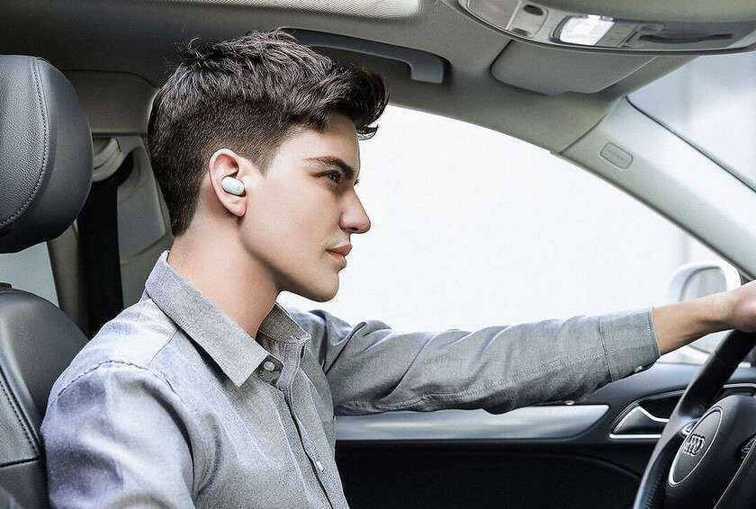 Молодой мужчина с наушником Xiaomi Mi Bluetooth Headset Mini в машине в профиль