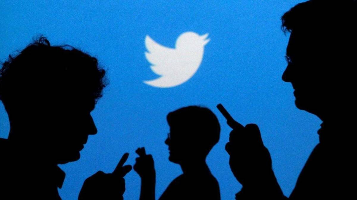 силуэты людей с мобильными телефонами на фоне логотипа Twitter
