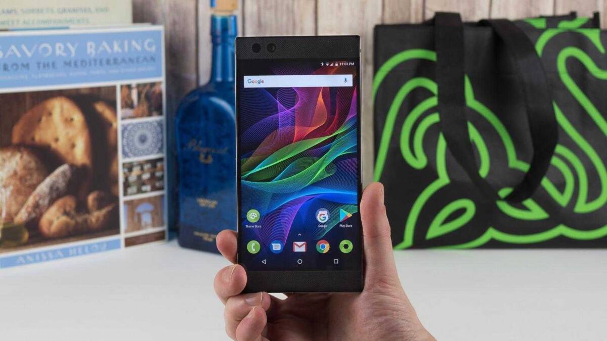 Ручная рука держит смартфон Razer Phone 2 с множеством приложений на экране