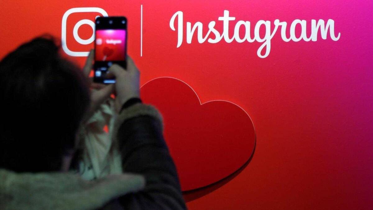 Человек фотографирует логотип Instagram на красной стене