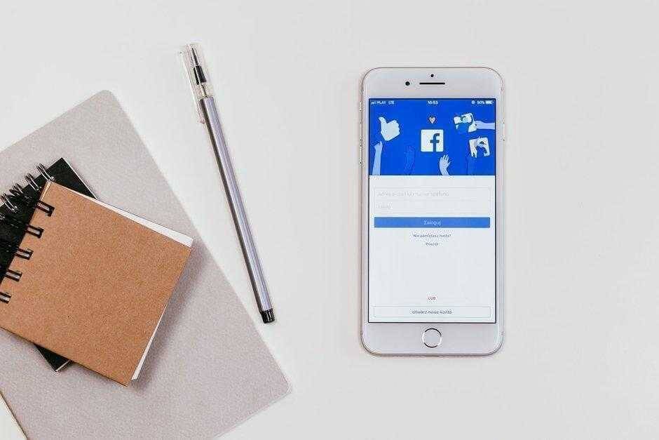 Смартфон iPhone с экраном входа в Facebook и блокнот рядом