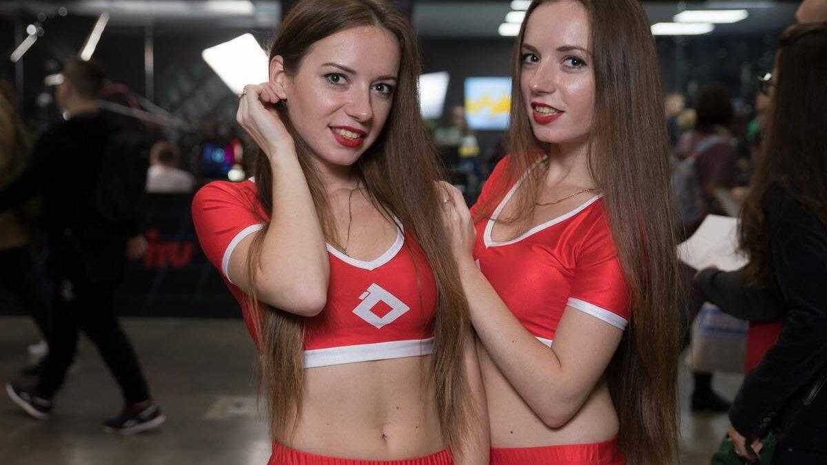 Две девушки в красных спортивных костюмах на фоне конференции