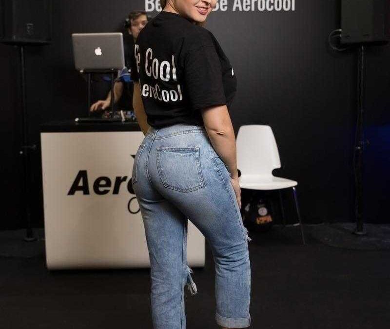 Девушка с новыми кроссовками и светлой прической на фоне стенда AeroCool