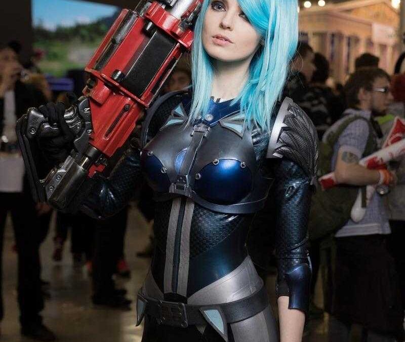 Косплей девушки с голубыми волосами в костюме будущего и оружием на популярной ярмарке ИгроМир 2018
